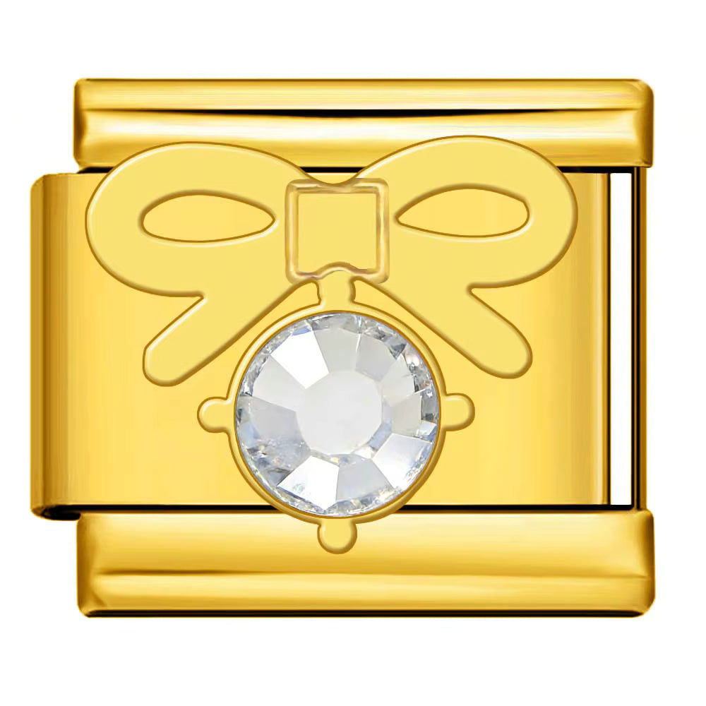 Gold charm with a bow design and clear gemstone on a white background