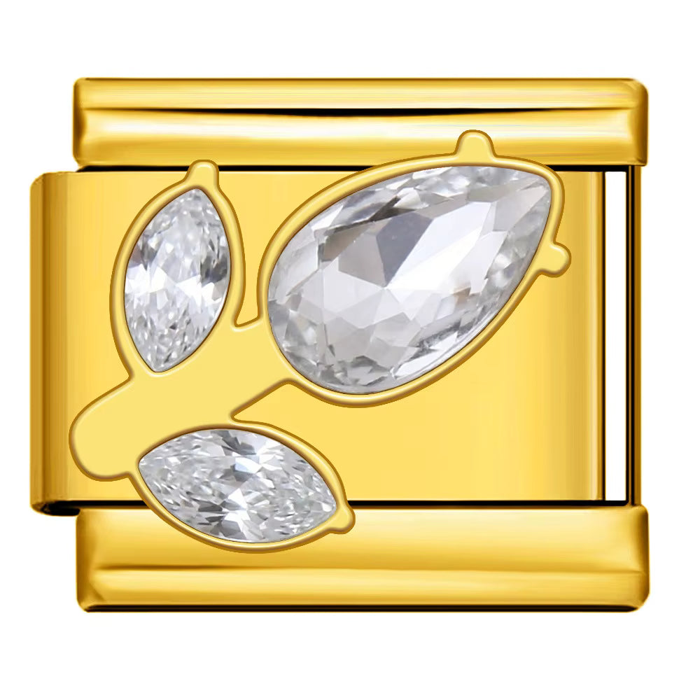 Gold charm with three clear gemstones on a white background