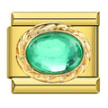 Gold charm with a green gemstone on a white background