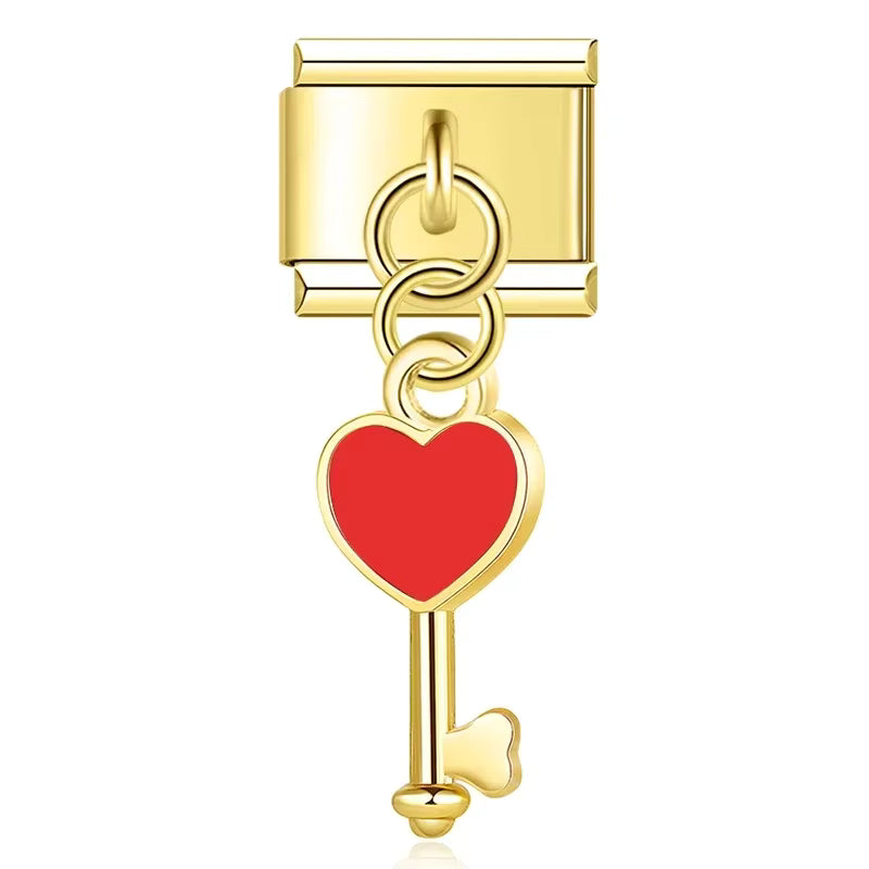 Gold key-shaped charm with a red heart on a white background