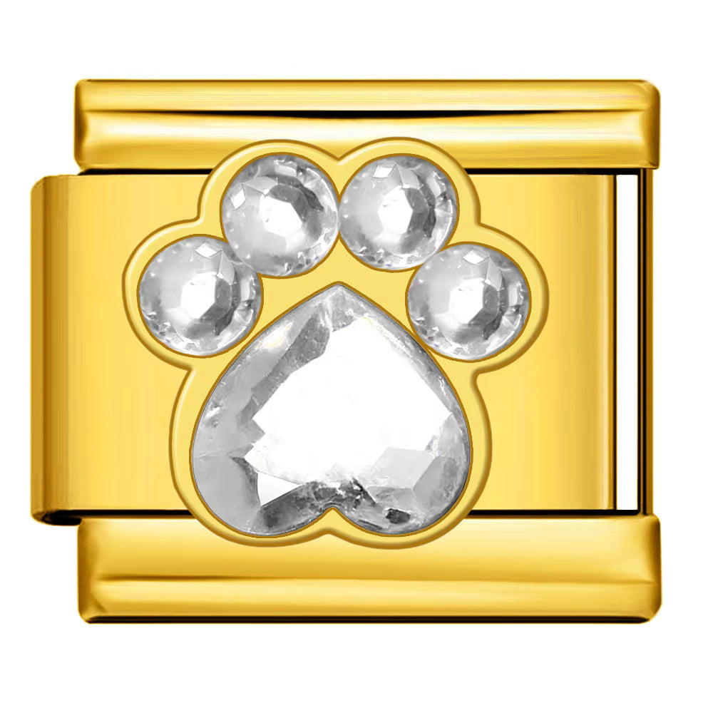 Gold charm with a paw print design featuring clear gemstones on a white background