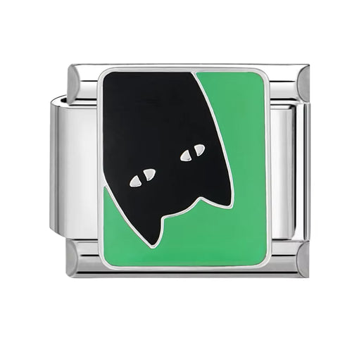 silver charm with black and green design on a white background