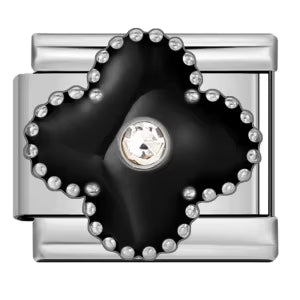 Silver charm with black clover and clear gemstone on a white background