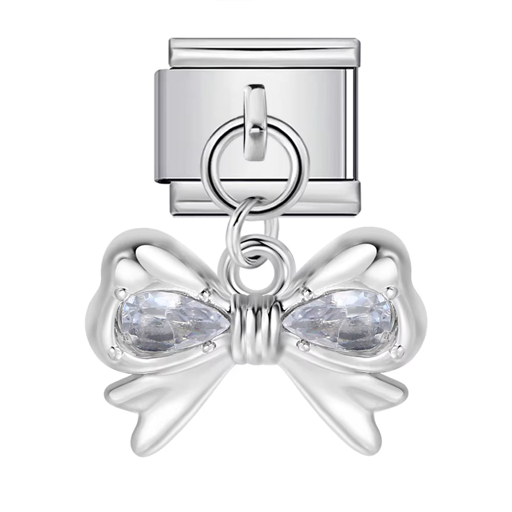 Silver bow-shaped charm with teardrop-shaped crystals on a white background