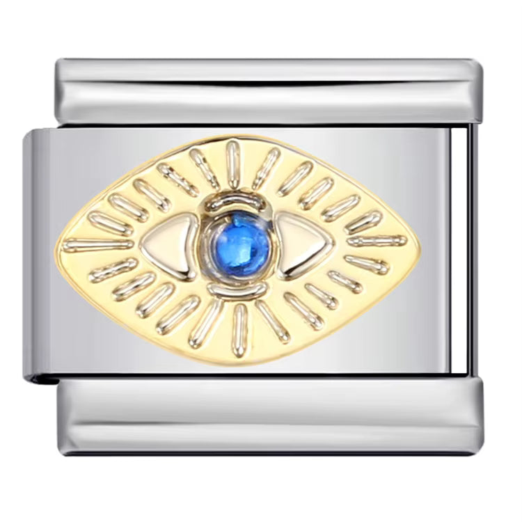 Silver charm with gold eye design and blue gemstone on a white background