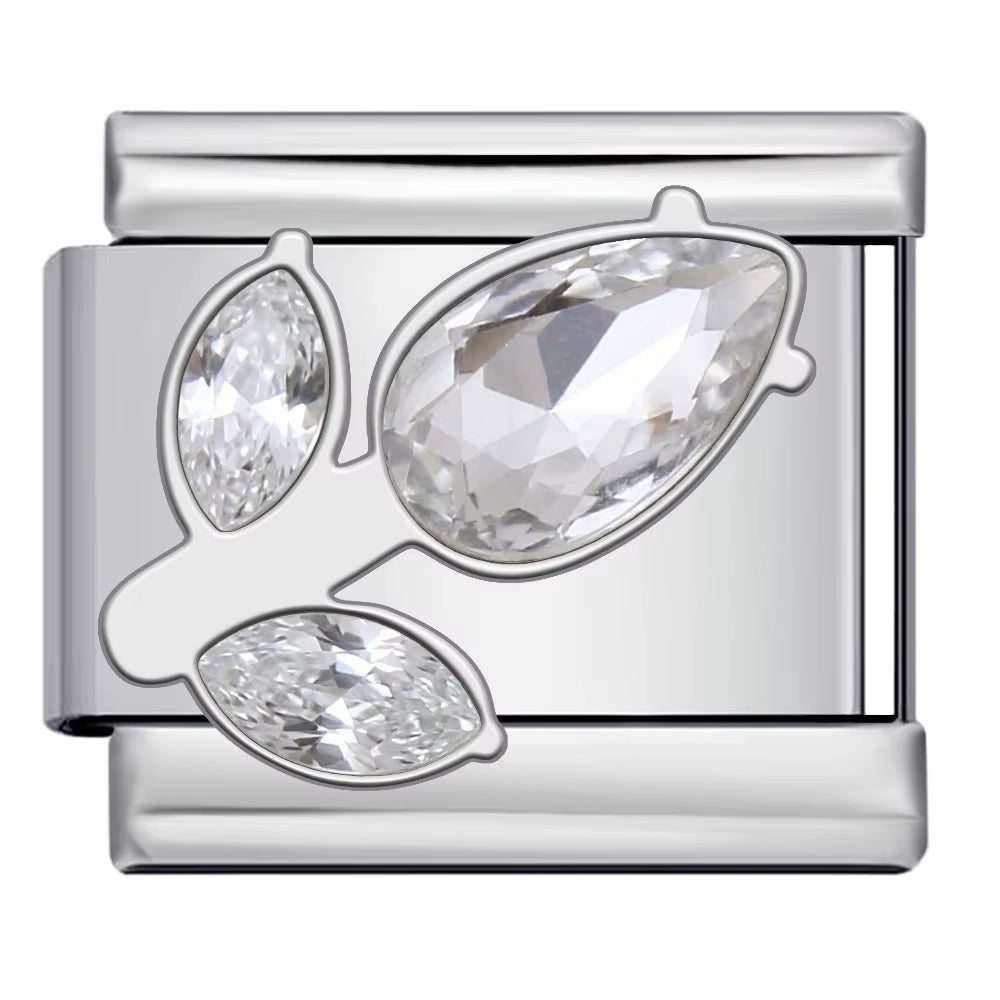 Silver charm with three clear gemstones on a white background