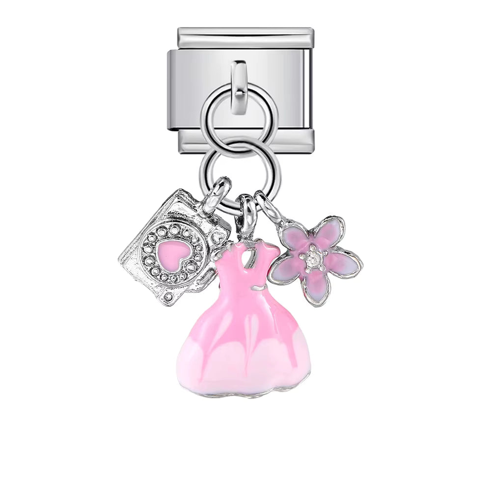 Silver charm with pink dress, camera, and flower on a white background